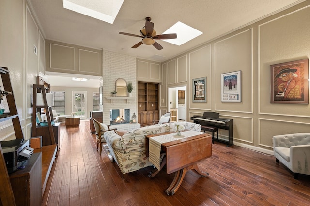 3907 Meadow Dr, Grapevine, TX 76051 - living area featuring a decorative wall, a skylight, ceiling fan, a fireplace, and dark wood-type flooring