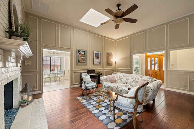 3907 Meadow Dr, Grapevine, TX 76051 - living room with a decorative wall, a fireplace, dark wood-style floors, ceiling fan, and a skylight