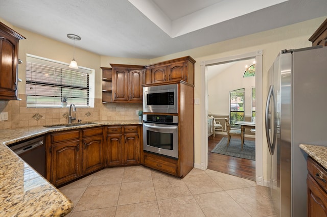 3907 Meadow Dr, Grapevine, TX 76051 - kitchen featuring appliances with stainless steel finishes, a sink, decorative backsplash, light stone counters, and healthy amount of natural light