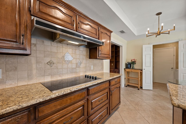 3907 Meadow Dr, Grapevine, TX 76051 - kitchen with black electric cooktop, under cabinet range hood, backsplash, light tile patterned flooring, and a chandelier