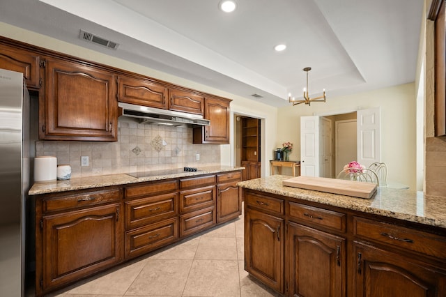 3907 Meadow Dr, Grapevine, TX 76051 - kitchen with a chandelier, a tray ceiling, tasteful backsplash, under cabinet range hood, and freestanding refrigerator
