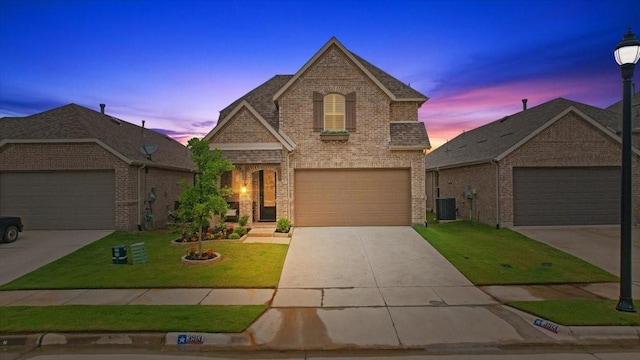 3913 Southbend Ct, Denison, TX 75020 - french provincial home featuring brick siding, a front lawn, driveway, an attached garage, and central AC unit