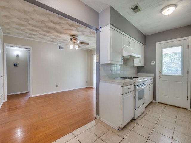 2504 W Rochelle Rd, Irving, TX 75062 - kitchen with white range, a ceiling fan, under cabinet range hood, light countertops, and white cabinets