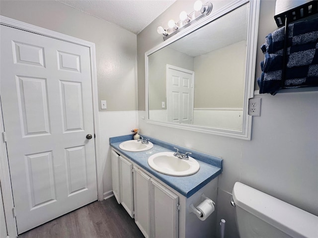 3007 Gaines St, Bossier City, LA 71111 - bathroom featuring wood finished floors, double vanity, toilet, and a textured ceiling