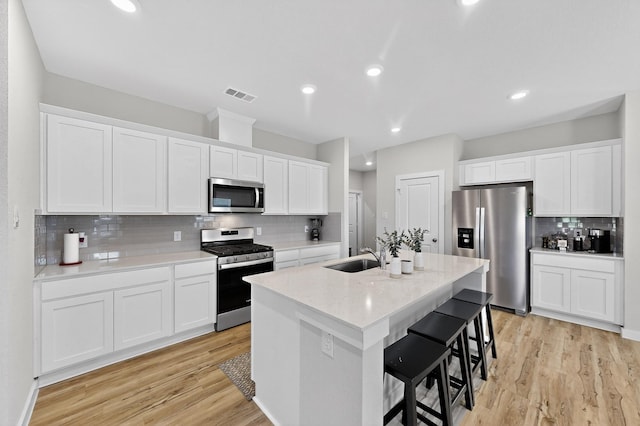 403 Pendant Dr, Royse City, TX 75189 - kitchen with stainless steel appliances, a sink, decorative backsplash, a center island with sink, and light wood finished floors