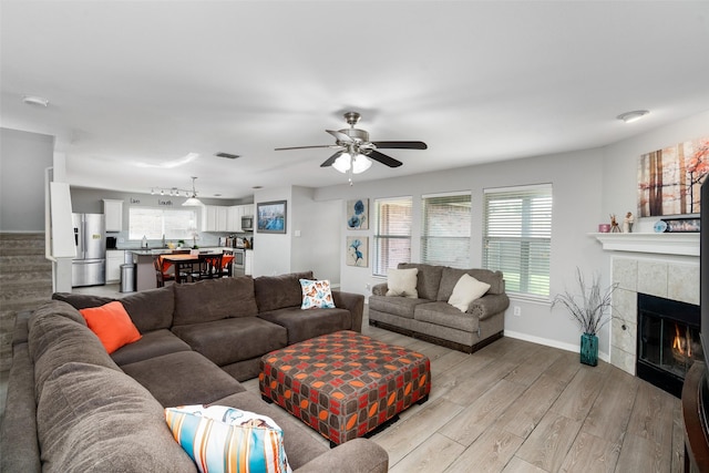 303 Highland Glen Dr, Wylie, TX 75098 - living area with light wood-type flooring, ceiling fan, a tile fireplace, stairs, and baseboards