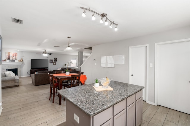 303 Highland Glen Dr, Wylie, TX 75098 - kitchen with a ceiling fan, light wood finished floors, a center island, a tiled fireplace, and open floor plan