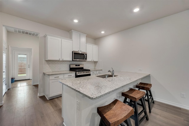 2705 Hancock Ln, Celina, TX 75009 - kitchen with stainless steel appliances, dark wood-style flooring, a sink, white cabinetry, and a breakfast bar area