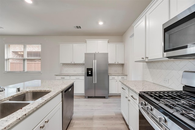 2705 Hancock Ln, Celina, TX 75009 - kitchen featuring stainless steel appliances, light wood-style floors, white cabinets, recessed lighting, and backsplash