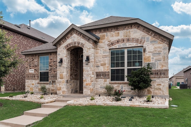 2705 Hancock Ln, Celina, TX 75009 - french country inspired facade featuring central AC unit, a front yard, stone siding, and a shingled roof