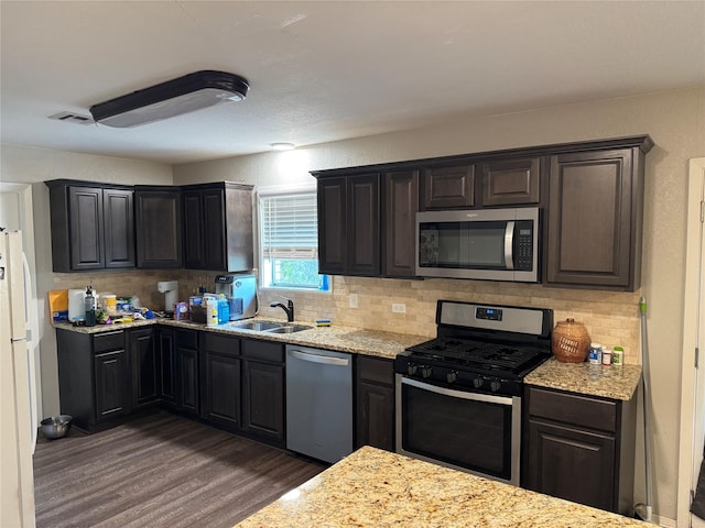 917 Susan St, Robinson, TX 76706 - kitchen with stainless steel appliances, a sink, dark wood-style floors, decorative backsplash, and light stone counters