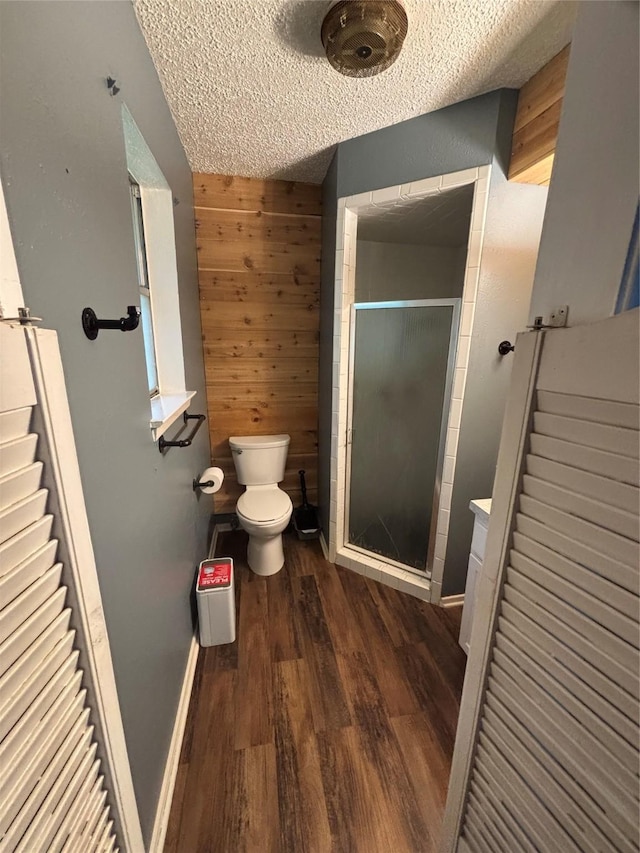 621 Lynnewood Ave, Burleson, TX 76028 - full bathroom featuring toilet, a shower stall, wood finished floors, a textured ceiling, and wood walls