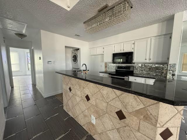 3404 W Country Club Dr Unit 264, Irving, TX 75038 - kitchen with stainless steel electric range oven, black microwave, stacked washer and clothes dryer, a textured ceiling, and dark countertops