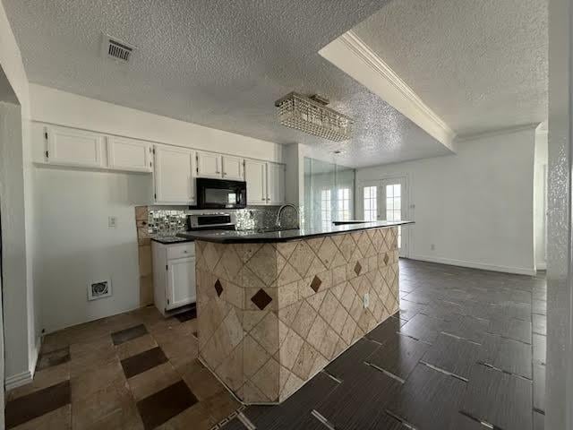 3404 W Country Club Dr Unit 264, Irving, TX 75038 - kitchen with black microwave, a textured ceiling, stove, white cabinets, and dark countertops