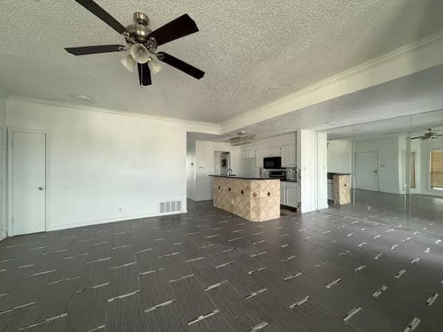 3404 W Country Club Dr Unit 264, Irving, TX 75038 - unfurnished living room with a textured ceiling, ceiling fan, crown molding, and dark colored carpet