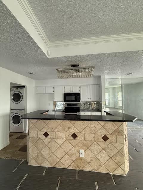 3404 W Country Club Dr Unit 264, Irving, TX 75038 - kitchen featuring a textured ceiling, black microwave, stacked washer and clothes dryer, dark countertops, and stainless steel range oven