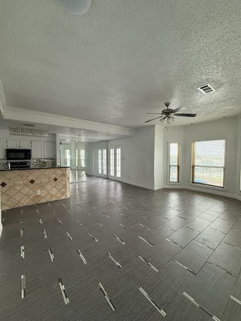 3404 W Country Club Dr Unit 264, Irving, TX 75038 - unfurnished living room with plenty of natural light, a textured ceiling, and a ceiling fan