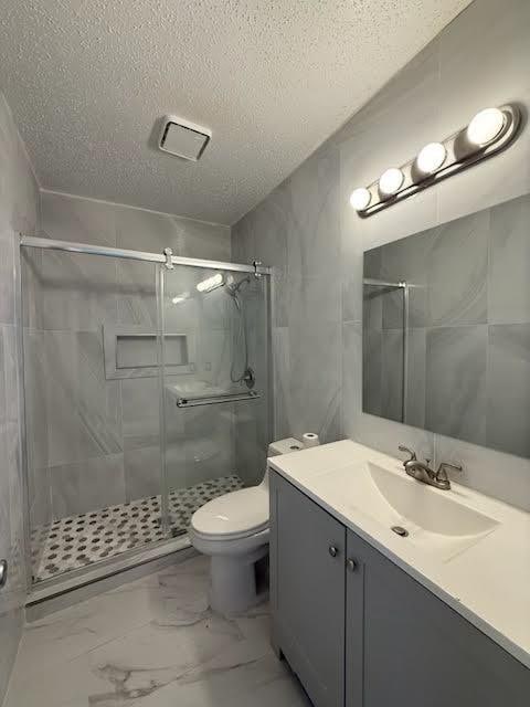 3404 W Country Club Dr Unit 264, Irving, TX 75038 - bathroom with marble look tiles, a textured ceiling, vanity, and a shower stall