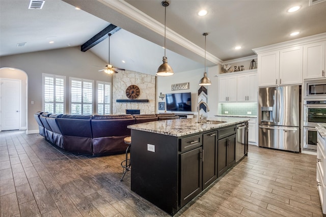 3900 Silent Water St, Mckinney, TX 75071 - kitchen featuring appliances with stainless steel finishes, a ceiling fan, white cabinets, a fireplace, and wood finished floors