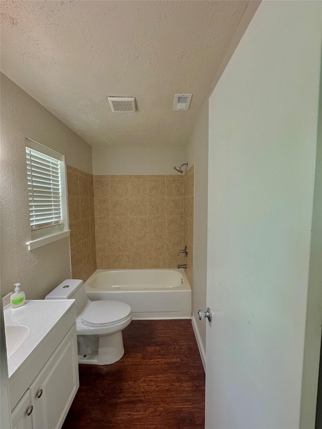 517 Gristmill Ln, Everman, TX 76140 - bathroom featuring a textured ceiling, vanity, wood finished floors, toilet, and shower / bathtub combination