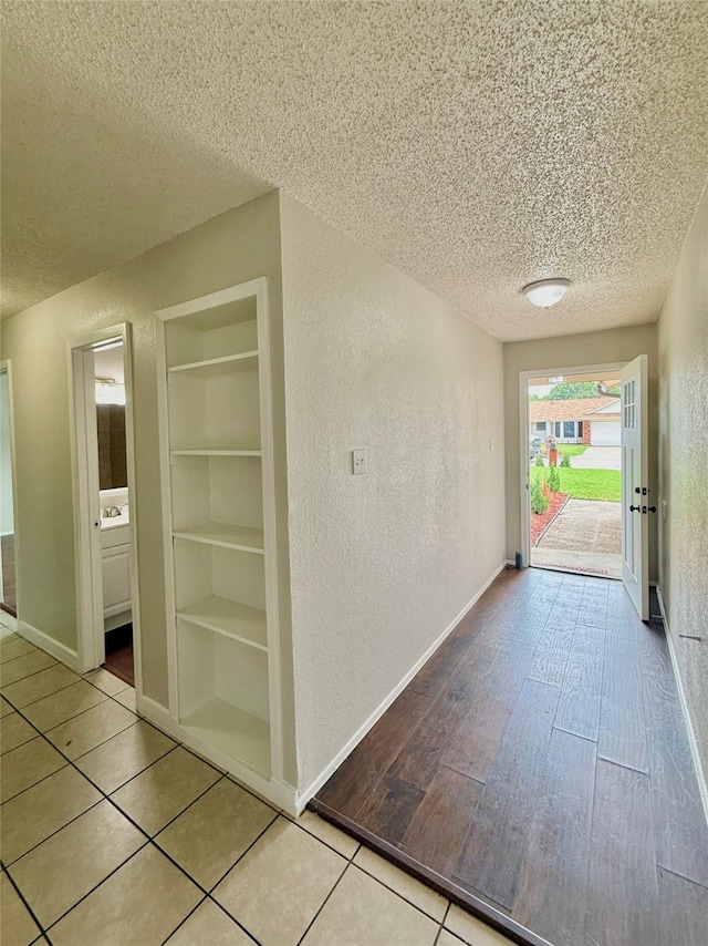 517 Gristmill Ln, Everman, TX 76140 - corridor featuring a textured ceiling, a textured wall, built in shelves, baseboards, and tile patterned flooring
