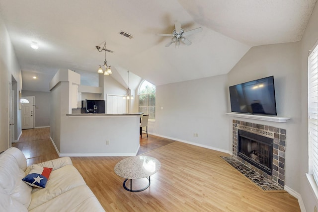824 Ingleside Dr, Plano, TX 75075 - living area featuring a ceiling fan, a tiled fireplace, vaulted ceiling, wood finished floors, and baseboards