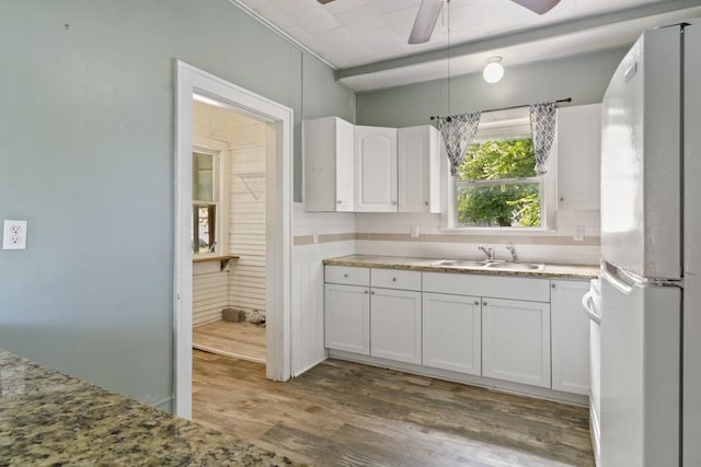 408 W Trinity St, Groesbeck, TX 76642 - kitchen with freestanding refrigerator, wood finished floors, white cabinets, a ceiling fan, and decorative backsplash