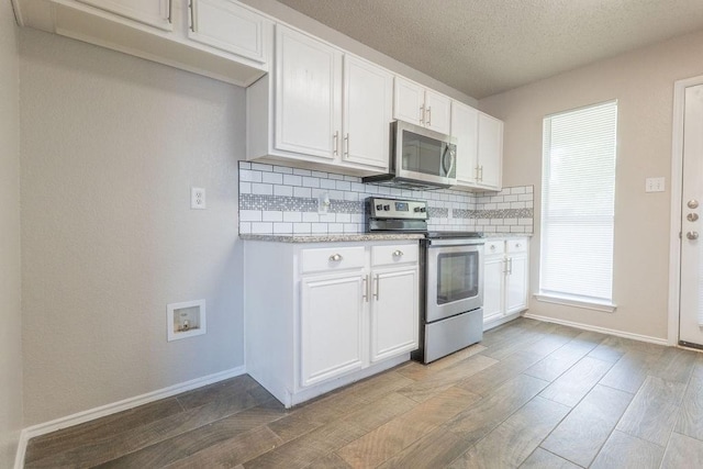 6104 Brookfall Dr, Arlington, TX 76018 - kitchen with appliances with stainless steel finishes, tasteful backsplash, wood finished floors, baseboards, and a textured ceiling