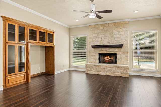 3600 Big Timber Ln, Granbury, TX 76049 - unfurnished living room with a stone fireplace, a ceiling fan, a textured ceiling, dark wood-style flooring, and crown molding