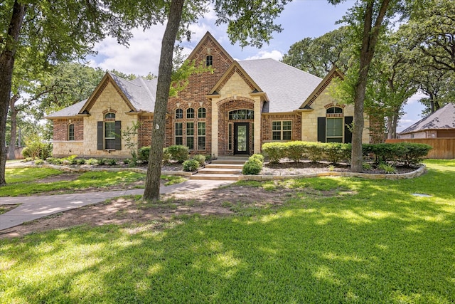 3600 Big Timber Ln, Granbury, TX 76049 - french provincial home featuring stone siding, a front yard, brick siding, and roof with shingles