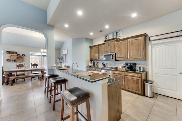 3113 Summer Dr, Little Elm, TX 75068 - kitchen featuring appliances with stainless steel finishes, a breakfast bar area, decorative backsplash, recessed lighting, and light tile patterned flooring