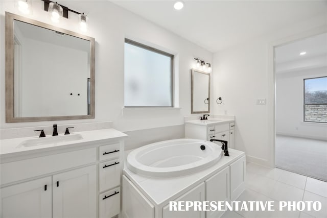 4180 Kestrel St, Prosper, TX 75078 - bathroom featuring two vanities, a bath, recessed lighting, tile patterned flooring, and baseboards