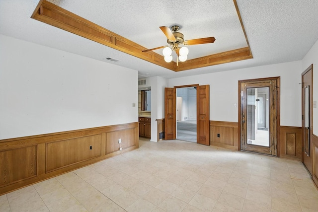 220 Simmons Dr, Coppell, TX 75019 - empty room featuring a raised ceiling, a textured ceiling, wainscoting, and ceiling fan