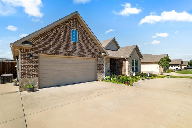768 Northside Dr, Pilot Point, TX 76258 - view of front of house featuring brick siding, driveway, stone siding, and a shingled roof