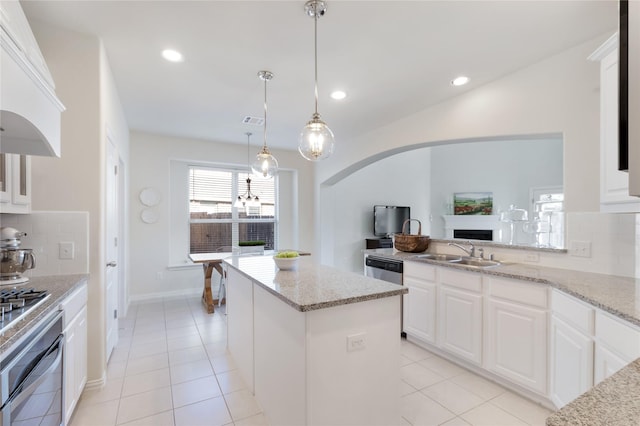 1409 Rose Bud Ct, Little Elm, TX 75068 - kitchen with a sink, wall oven, tasteful backsplash, a kitchen island, and arched walkways