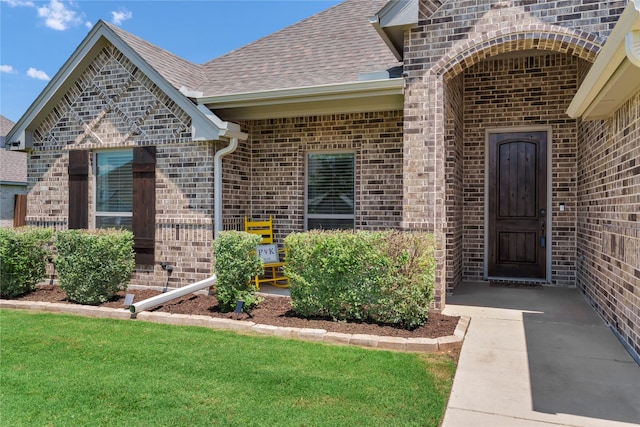 110 Oak View Dr, Godley, TX 76044 - view of exterior entry with brick siding, a shingled roof, and a yard