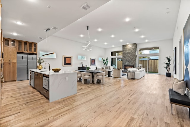 3940 N Cresthaven, Dallas, TX 75209 - kitchen with light wood-style flooring, stainless steel appliances, open floor plan, a center island with sink, and light countertops