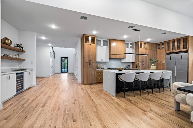3940 N Cresthaven, Dallas, TX 75209 - kitchen featuring beverage cooler, high quality fridge, a center island with sink, a breakfast bar, and light countertops