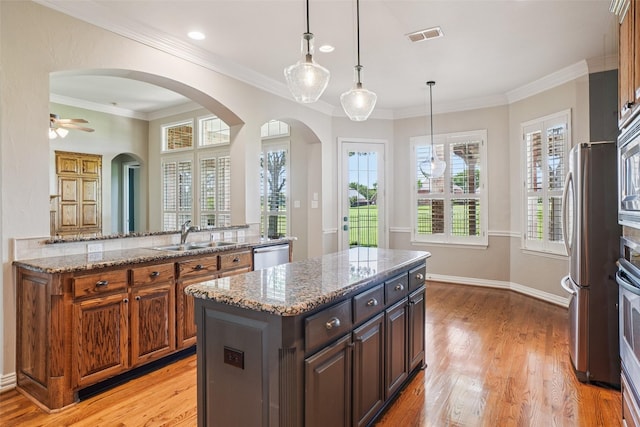8304 Old Hickory Ln, Mckinney, TX 75072 - kitchen featuring a sink, stainless steel appliances, a kitchen island, arched walkways, and light wood-style floors