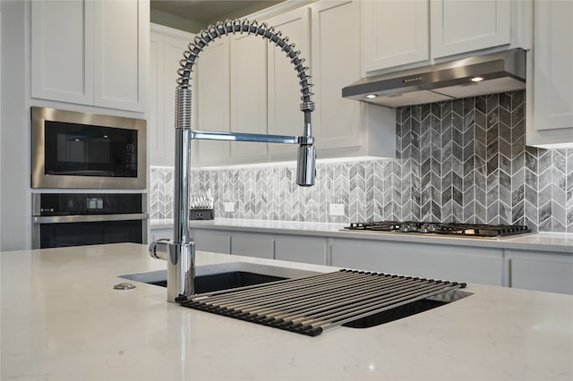 6133 Poolside Way, Royse City, TX 75189 - kitchen with under cabinet range hood, appliances with stainless steel finishes, white cabinets, and backsplash