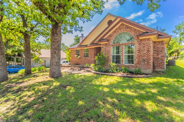 809 W Ball St, Weatherford, TX 76086 - view of front of house with brick siding, a front yard, central AC unit, and a chimney