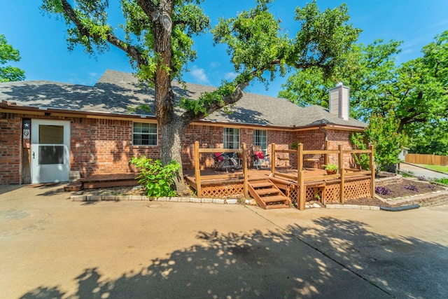809 W Ball St, Weatherford, TX 76086 - back of house featuring brick siding, a chimney, a wooden deck, and roof with shingles