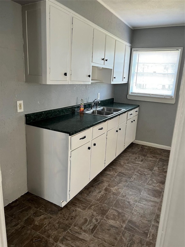 2907 W Collin St, Corsicana, TX 75110 - kitchen with a sink, dark countertops, white cabinetry, and a textured wall