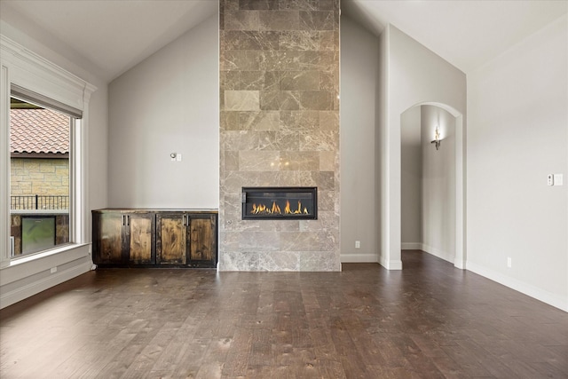 1209 Catalina Bay Blvd, Granbury, TX 76048 - unfurnished living room featuring arched walkways, hardwood / wood-style flooring, a fireplace, high vaulted ceiling, and baseboards