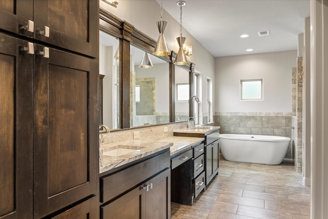 1209 Catalina Bay Blvd, Granbury, TX 76048 - bathroom featuring double vanity, a soaking tub, tile walls, wood finished floors, and wainscoting