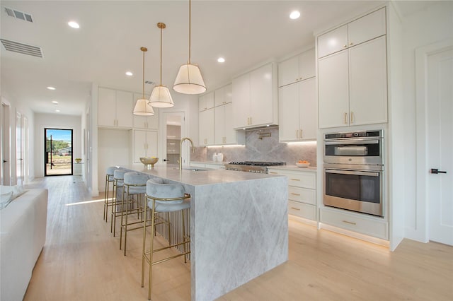 1903 Mcbroom St, Dallas, TX 75212 - kitchen featuring appliances with stainless steel finishes, a sink, tasteful backsplash, light wood-style flooring, and recessed lighting