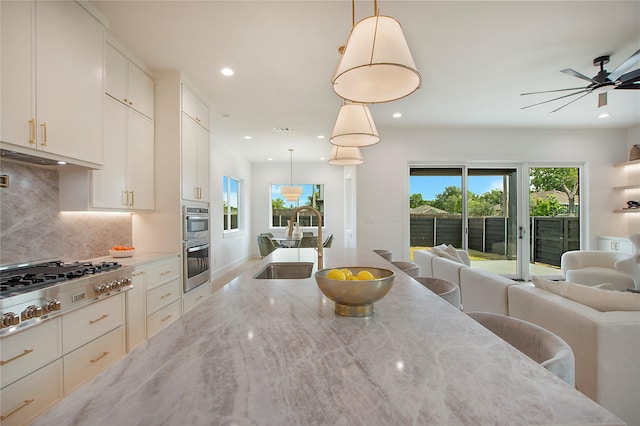 1903 Mcbroom St, Dallas, TX 75212 - kitchen featuring open floor plan, a sink, appliances with stainless steel finishes, backsplash, and light stone counters