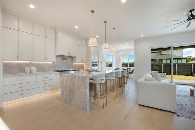 1903 Mcbroom St, Dallas, TX 75212 - kitchen featuring ceiling fan, light wood finished floors, backsplash, a breakfast bar, and oven