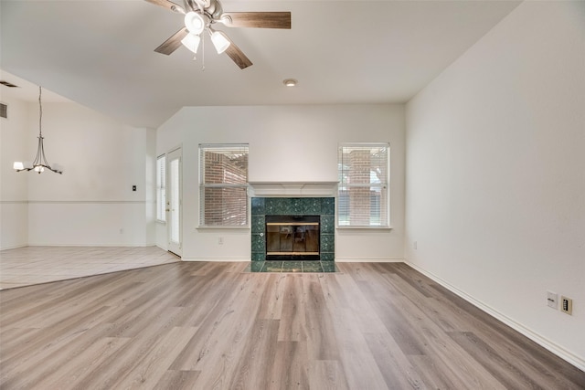 1213 Sonoma Dr, Allen, TX 75013 - unfurnished living room with wood finished floors, a ceiling fan, a tiled fireplace, a chandelier, and baseboards