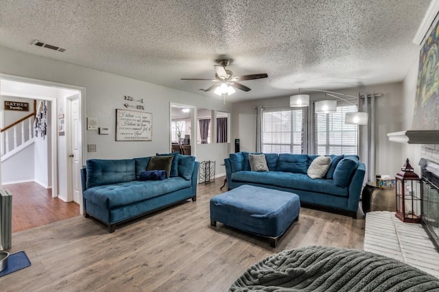 238 Browning Ln, Grand Prairie, TX 75052 - living room featuring a ceiling fan, stairway, wood finished floors, a textured ceiling, and a brick fireplace